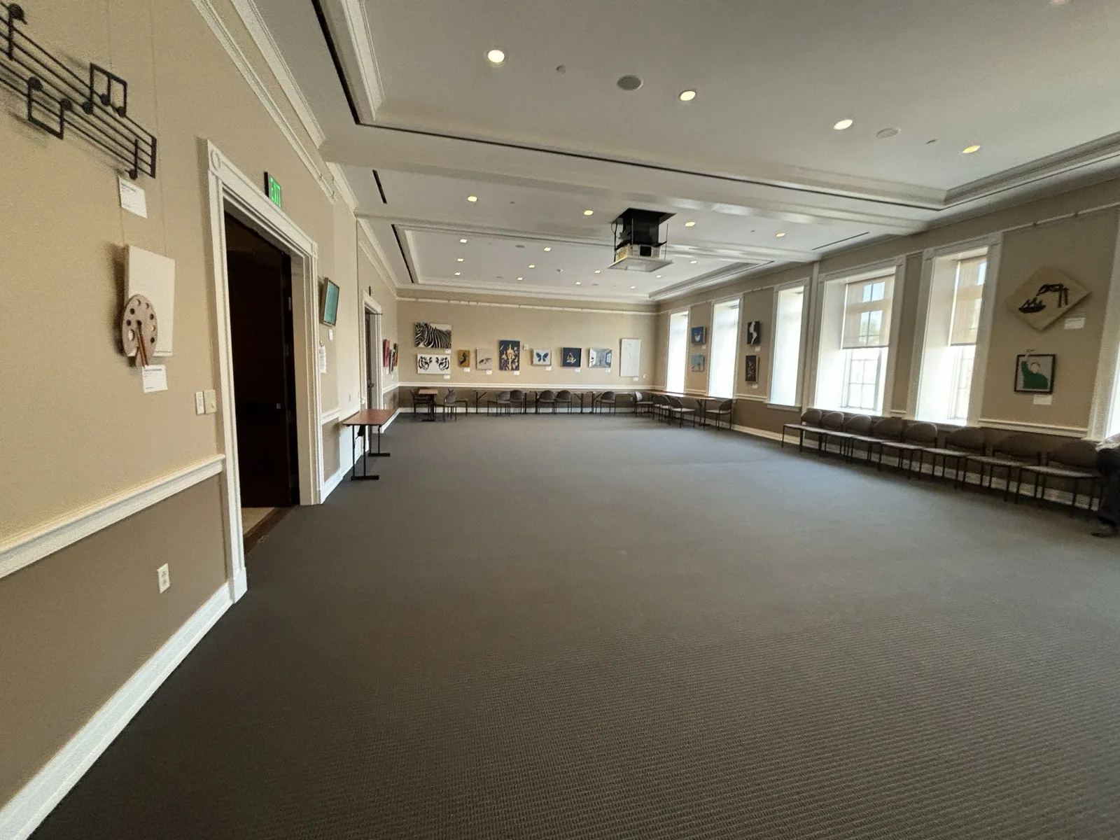 A large carpeted meeting room inside Alpharetta City Hall with recessed ceiling lights, framed art on the walls and chairs along the edges.