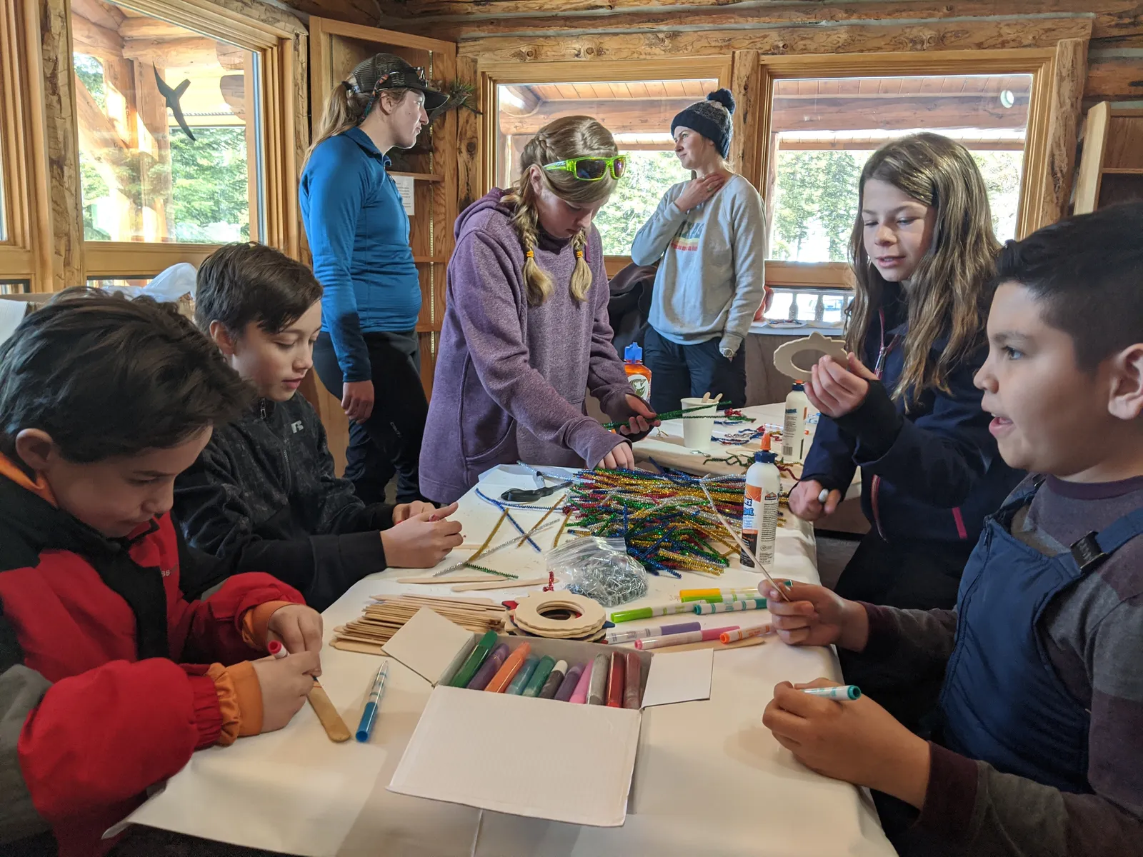 Children make Christmas ornaments at a craft table during a U.S. Forest Service kids' ski day; the Merry Maze ends with an ornament of each child's own to take home.